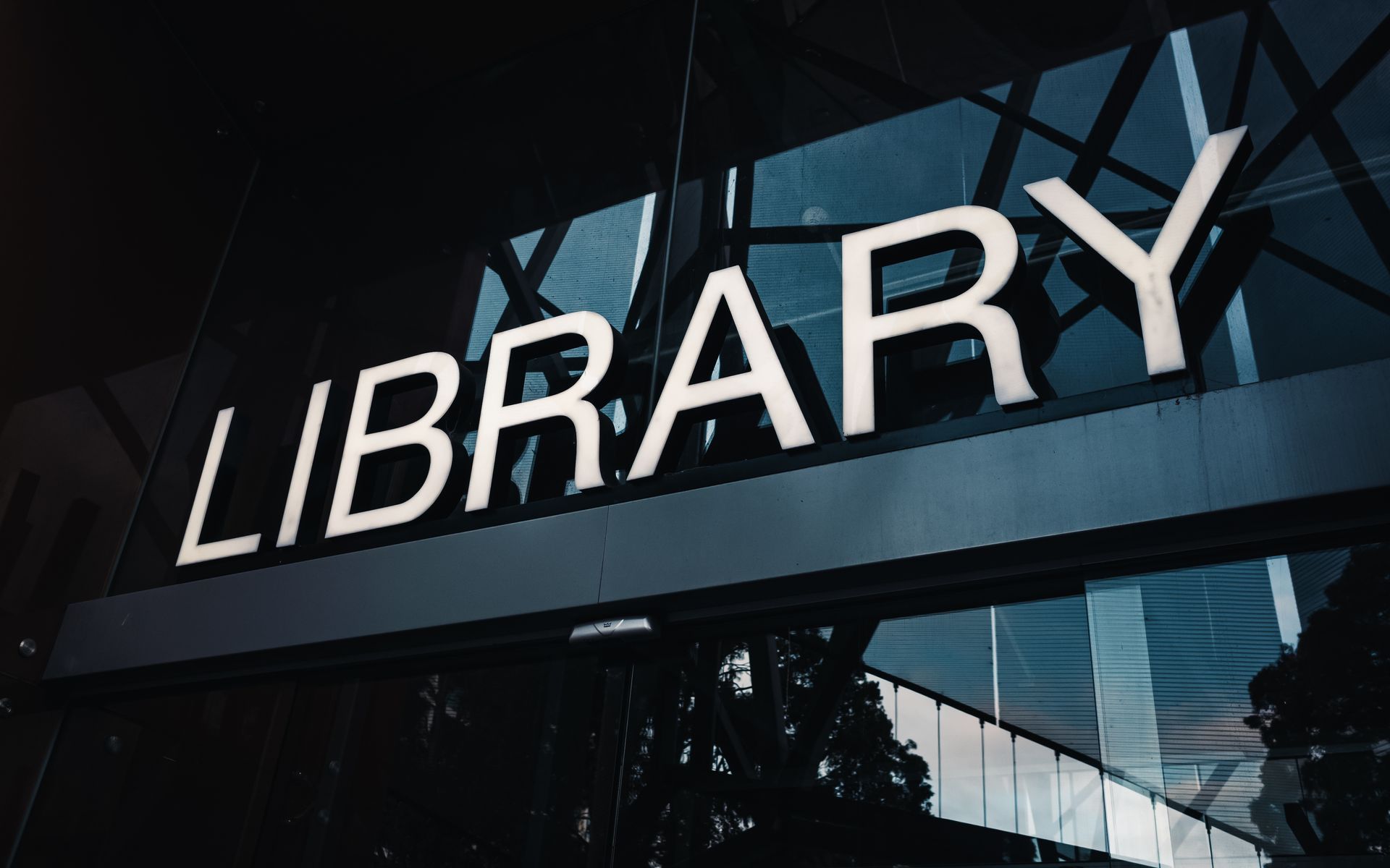 Library sign displayed on the glass exterior of a modern building.