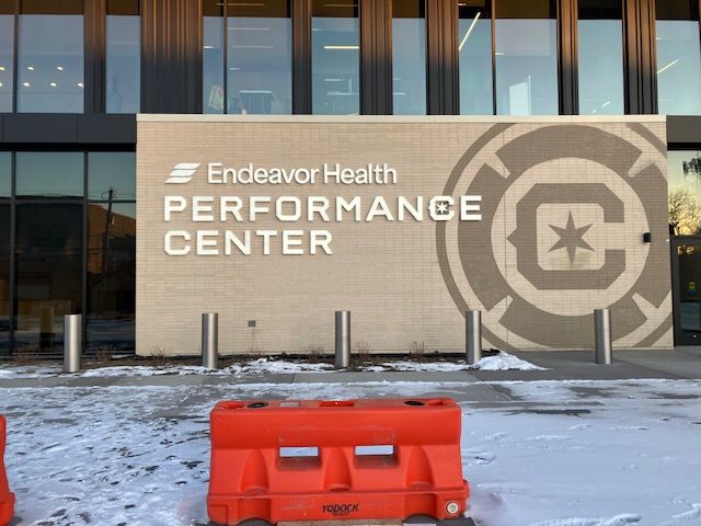 Endeavor Health Performance Center sign on brick wall beside orange barricade and snow-covered ground