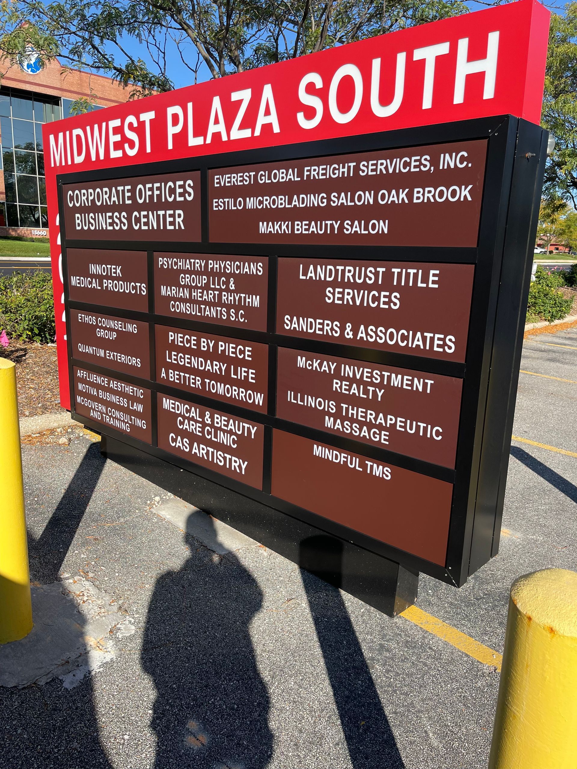Directory sign for Midwest Plaza South in front of the building, with red header and brown tenant panels.