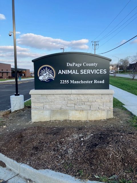 DuPage County Animal Services sign on a roadside stone base at dusk