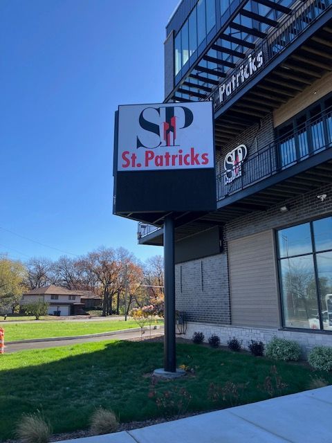 St. Patricks sign on a brick building with a clear blue sky and grassy lawn nearby