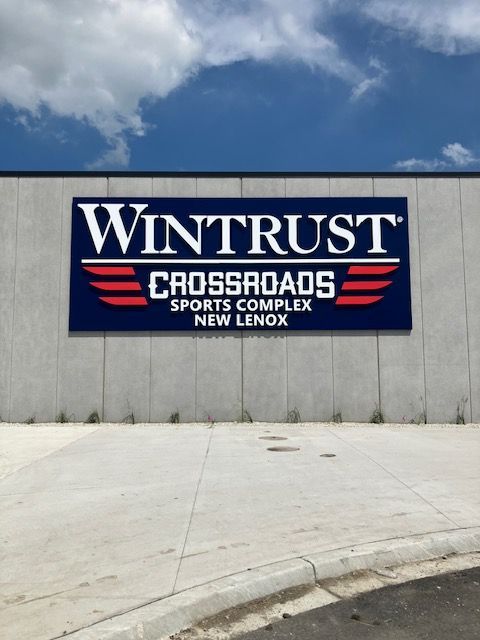 Wintrust Crossroads Sports Complex sign on a concrete wall under a blue sky
