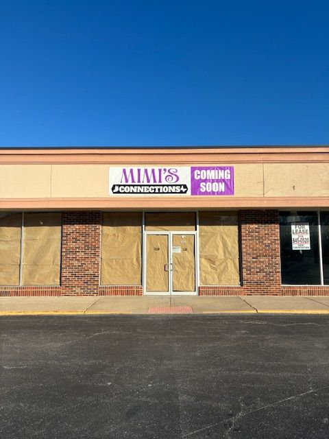 Closed storefront with boarded windows and a “COMING SOON” sign on a sunny strip mall exterior.
