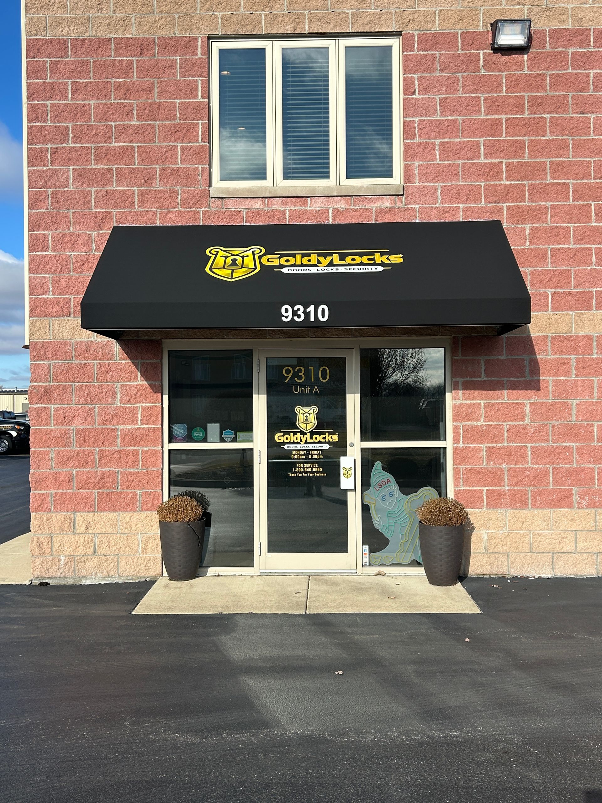 Brick storefront with black awning, glass door, and address 9310 above the entrance.