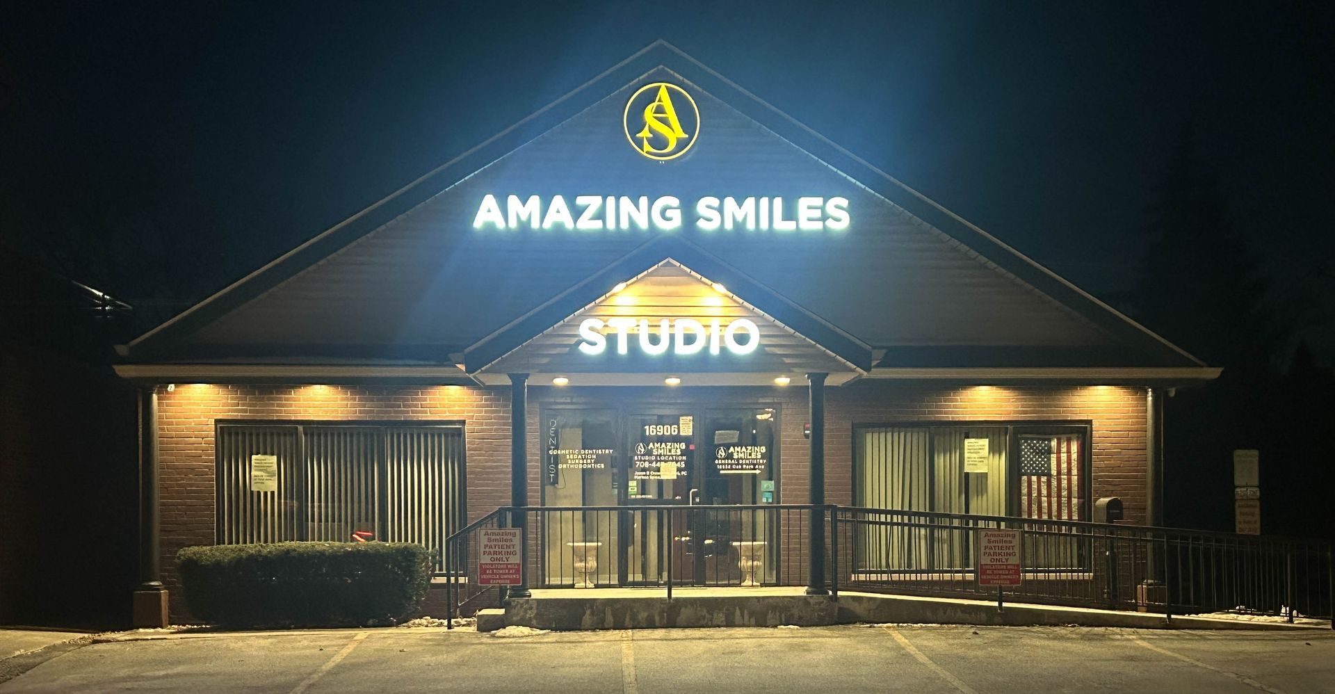 Night view of a storefront sign reading “Amazing Smiles Studio” with lit windows and entrance