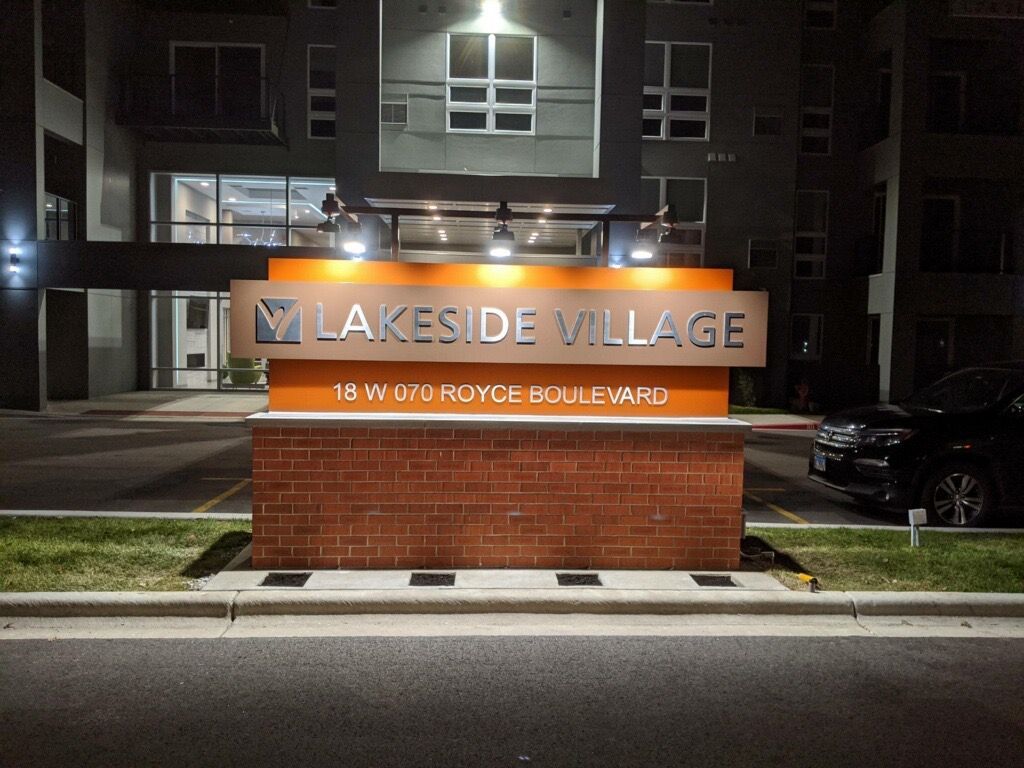 Lakeside Village sign illuminated at night in front of an apartment building