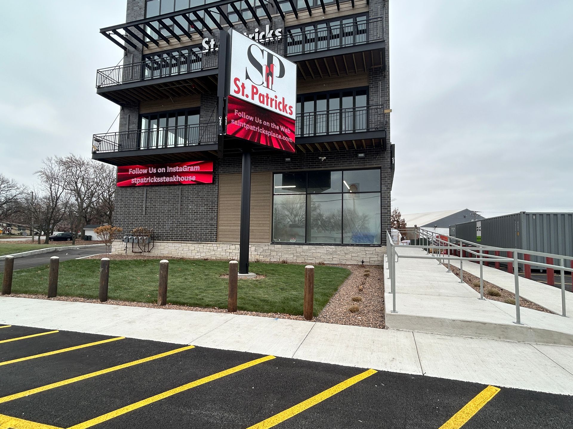 St. Philip’s sign on a modern building beside a parking lot and sidewalk under an overcast sky