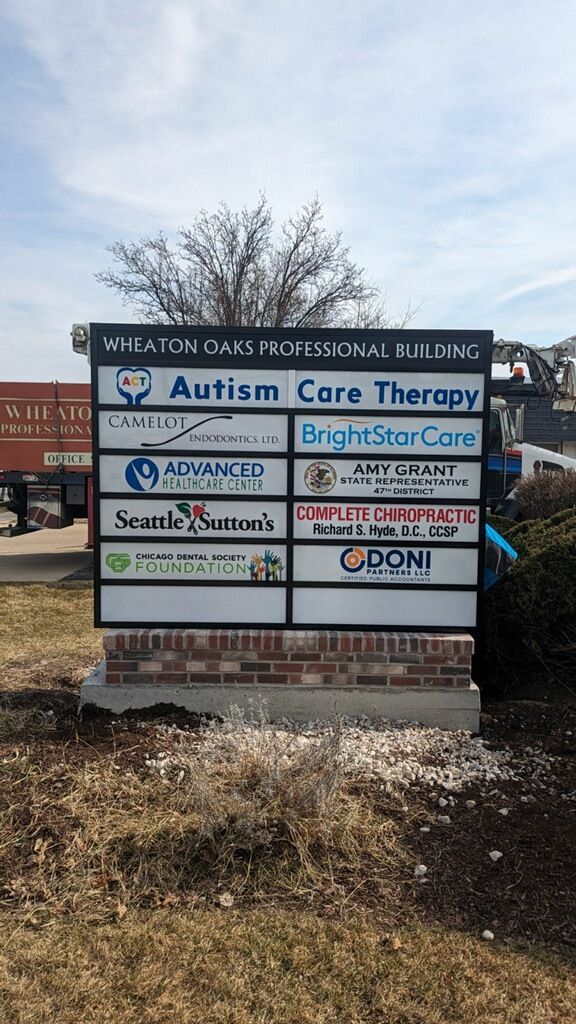 Sign board for multiple medical and therapy offices outside a brick building, including Autism Care Therapy.