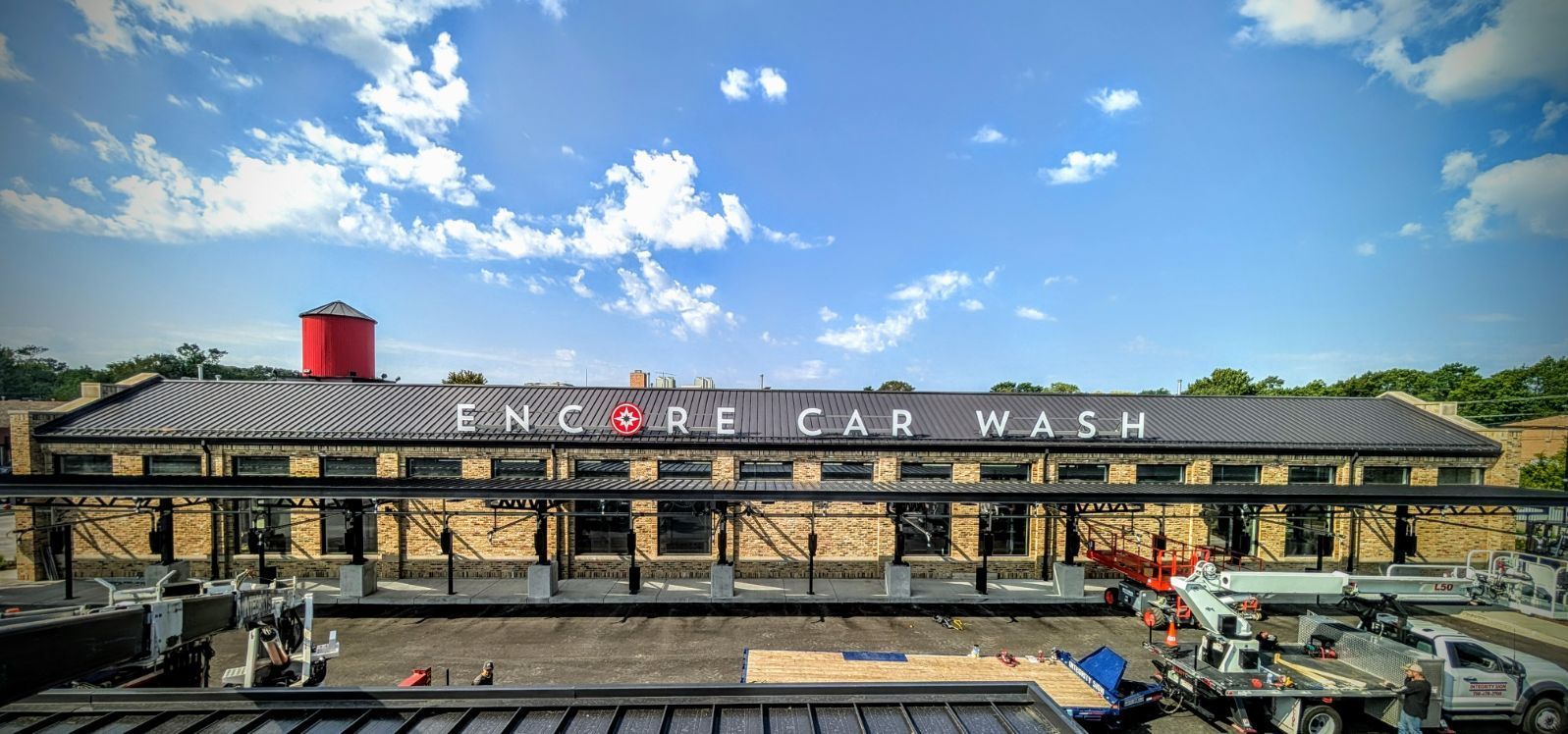 Exterior of Encore Car Wash with a red water tower under a blue sky