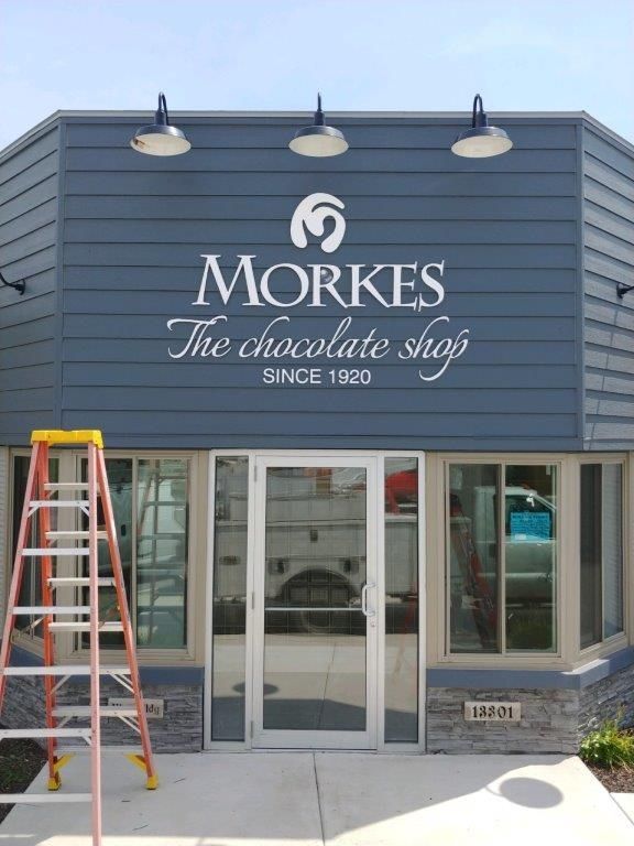 Morkes chocolate shop storefront with blue facade, glass doors, and a red ladder outside