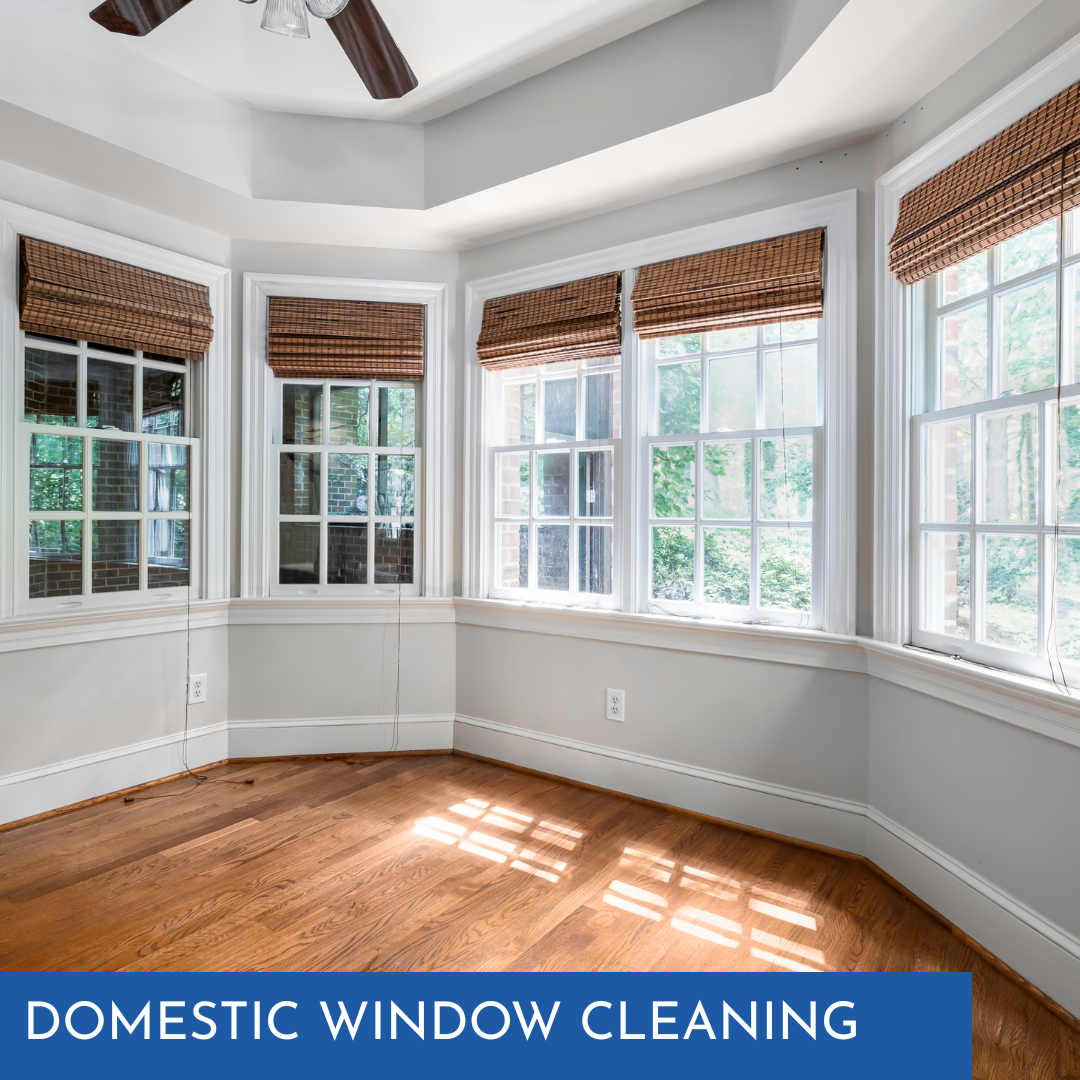 Empty, sunlit room with wooden floor, white walls, and multiple windows with brown shades; text: Domestic Window Cleaning.