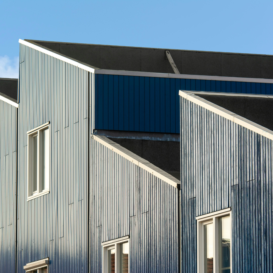 Blue-paneled buildings with white-framed windows against a clear blue sky.