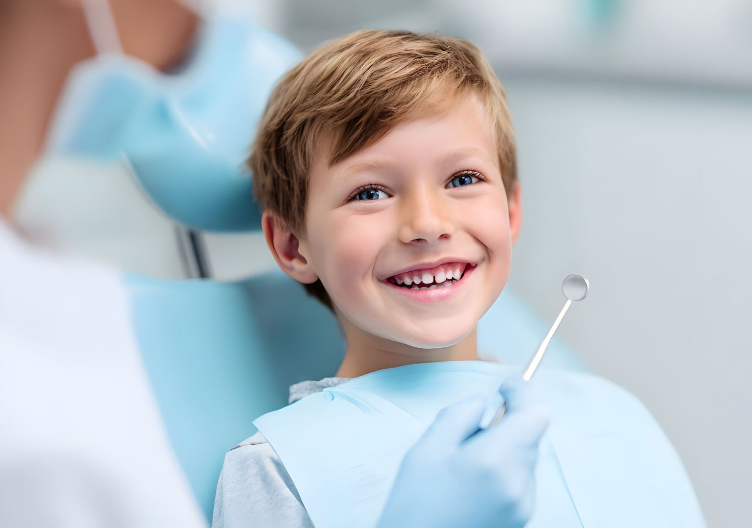 A child smiling while seated in a dental chair as a person in a blue glove holds a dental mirror.