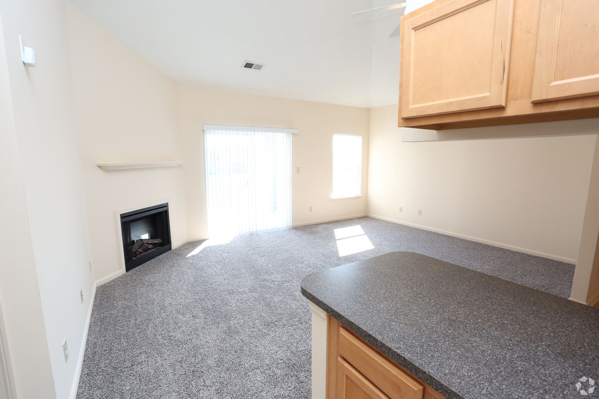 An empty living room with a fireplace and sliding glass doors.