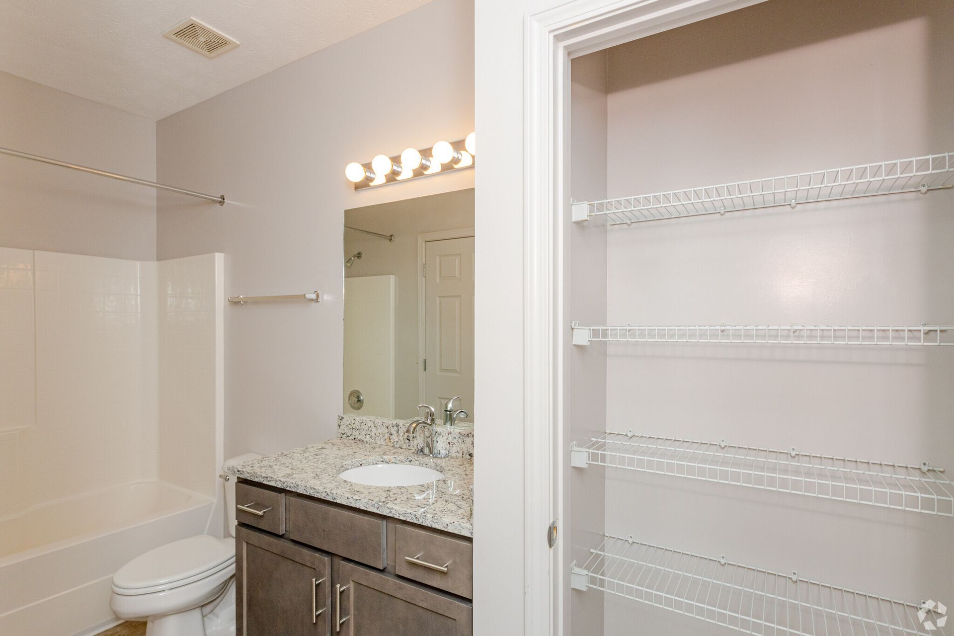 A bathroom with a toilet , sink , mirror and closet.