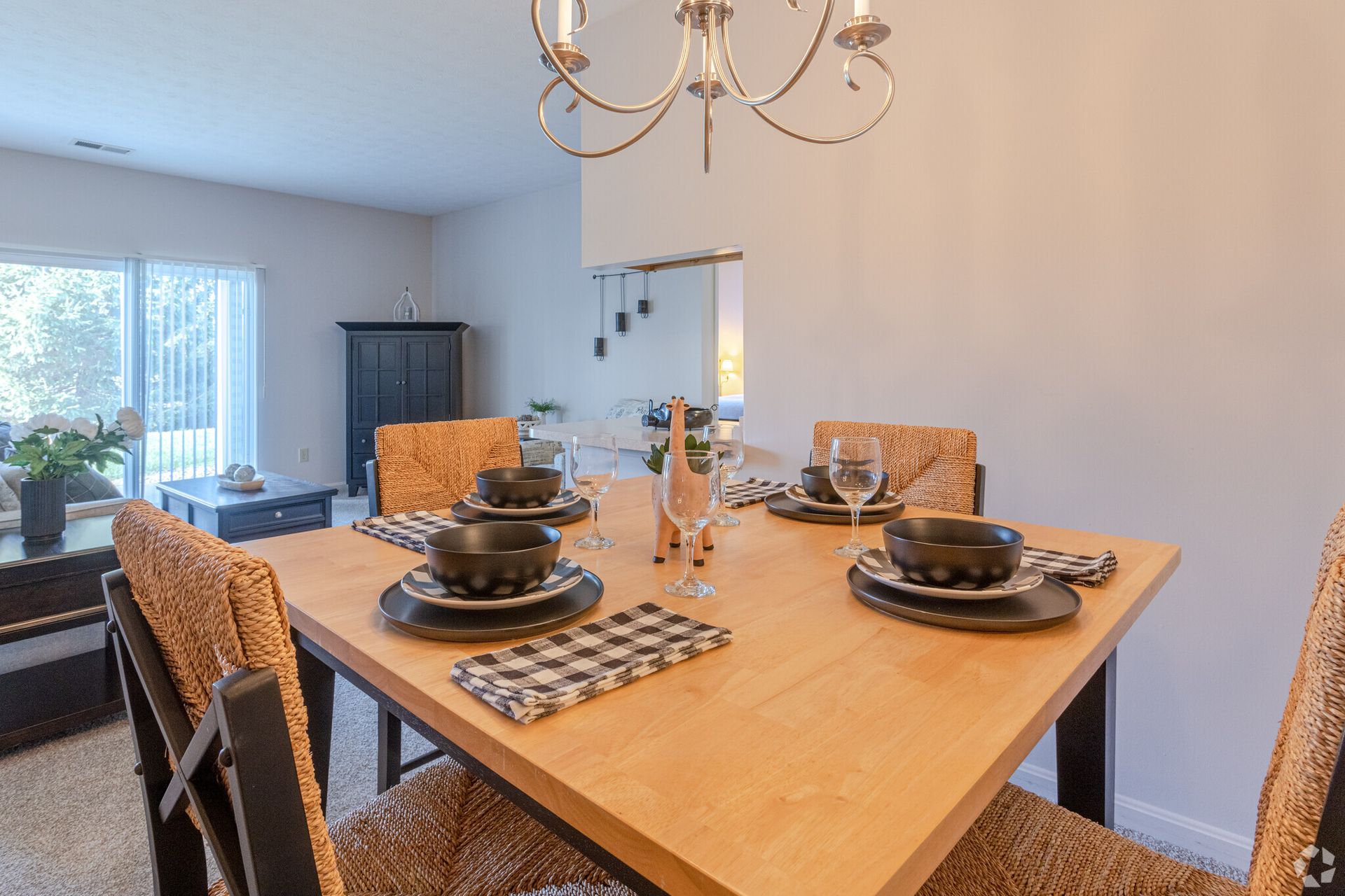 A dining room table with plates , bowls , glasses and a chandelier.