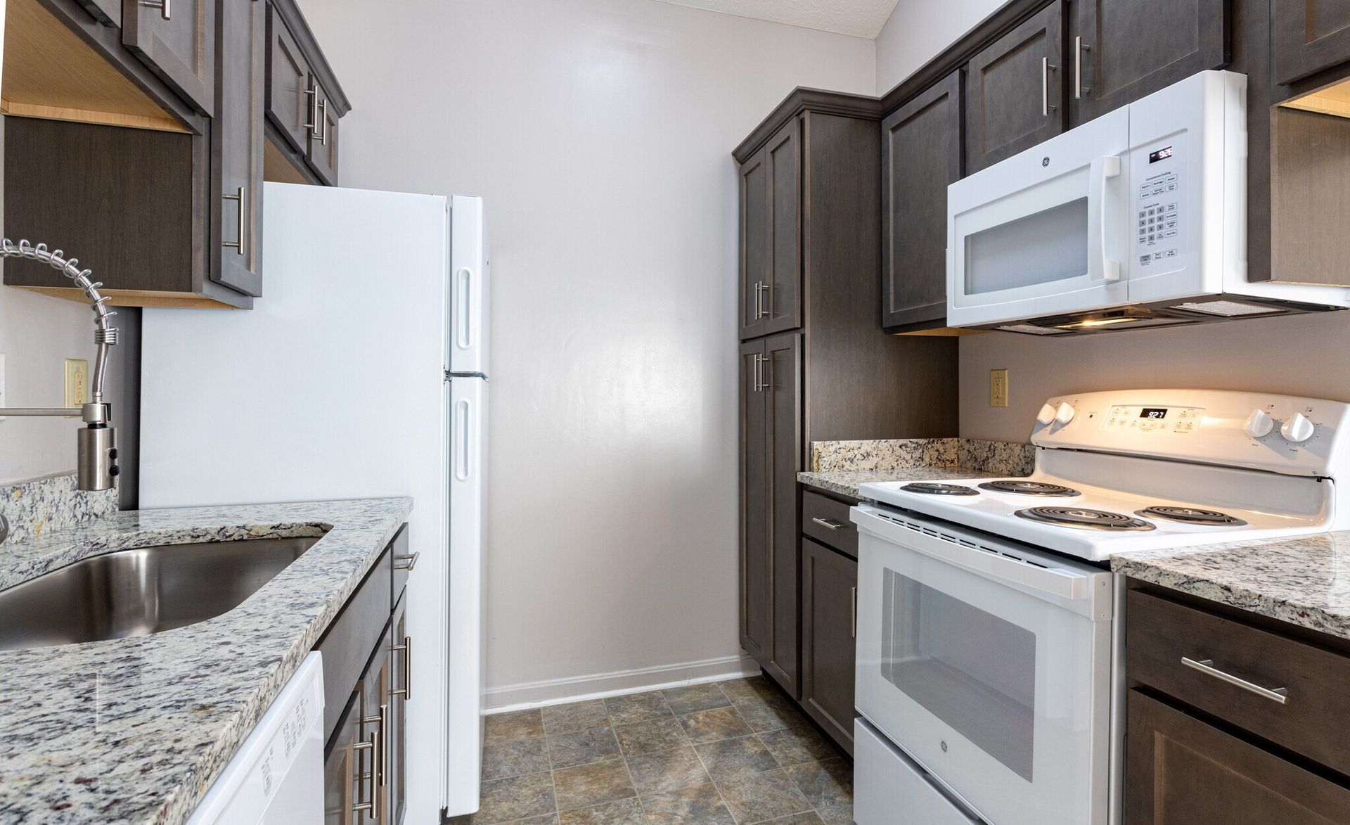 A kitchen with a refrigerator , stove , microwave and sink.