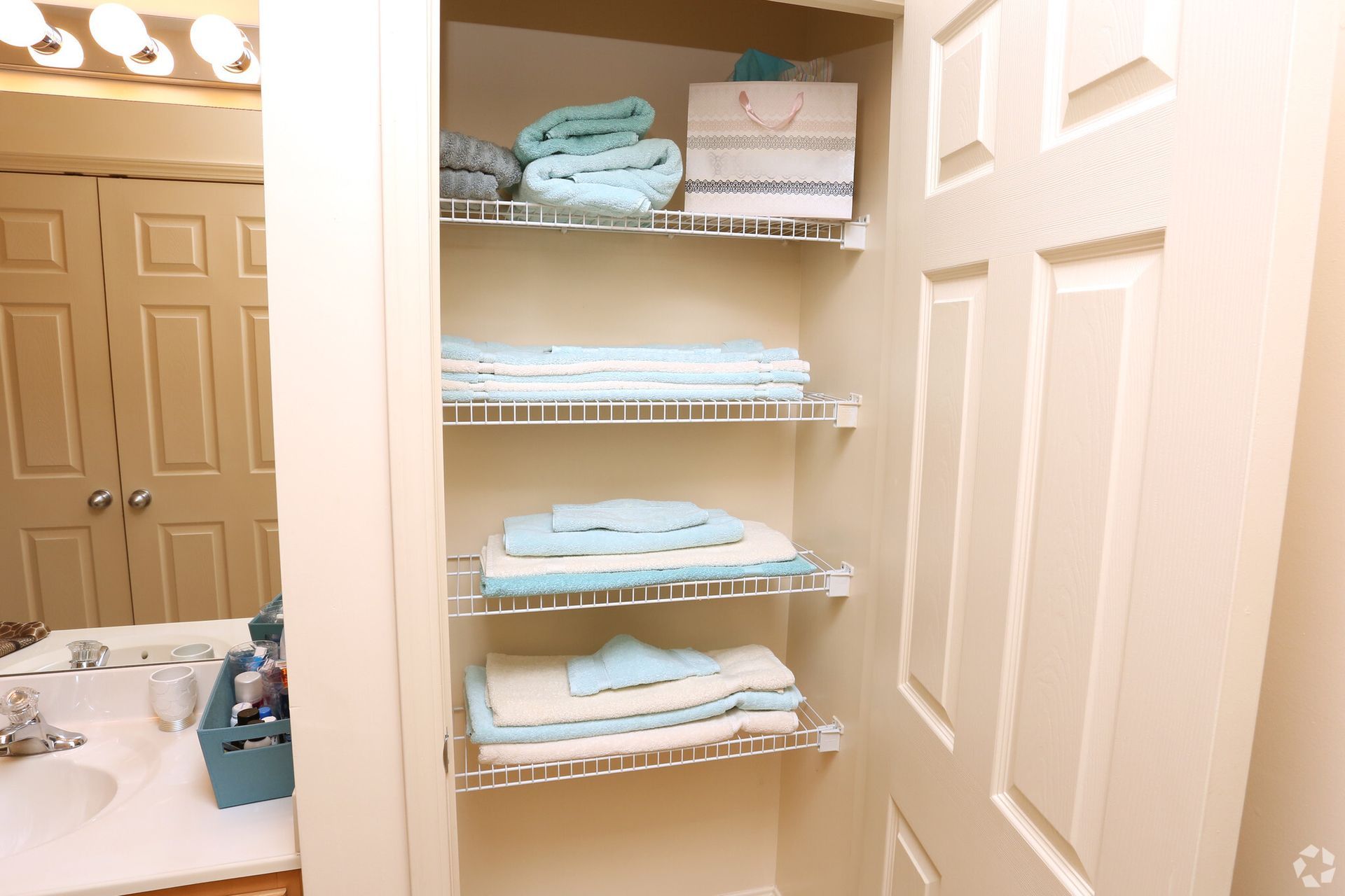 A bathroom with a closet filled with towels and a sink.
