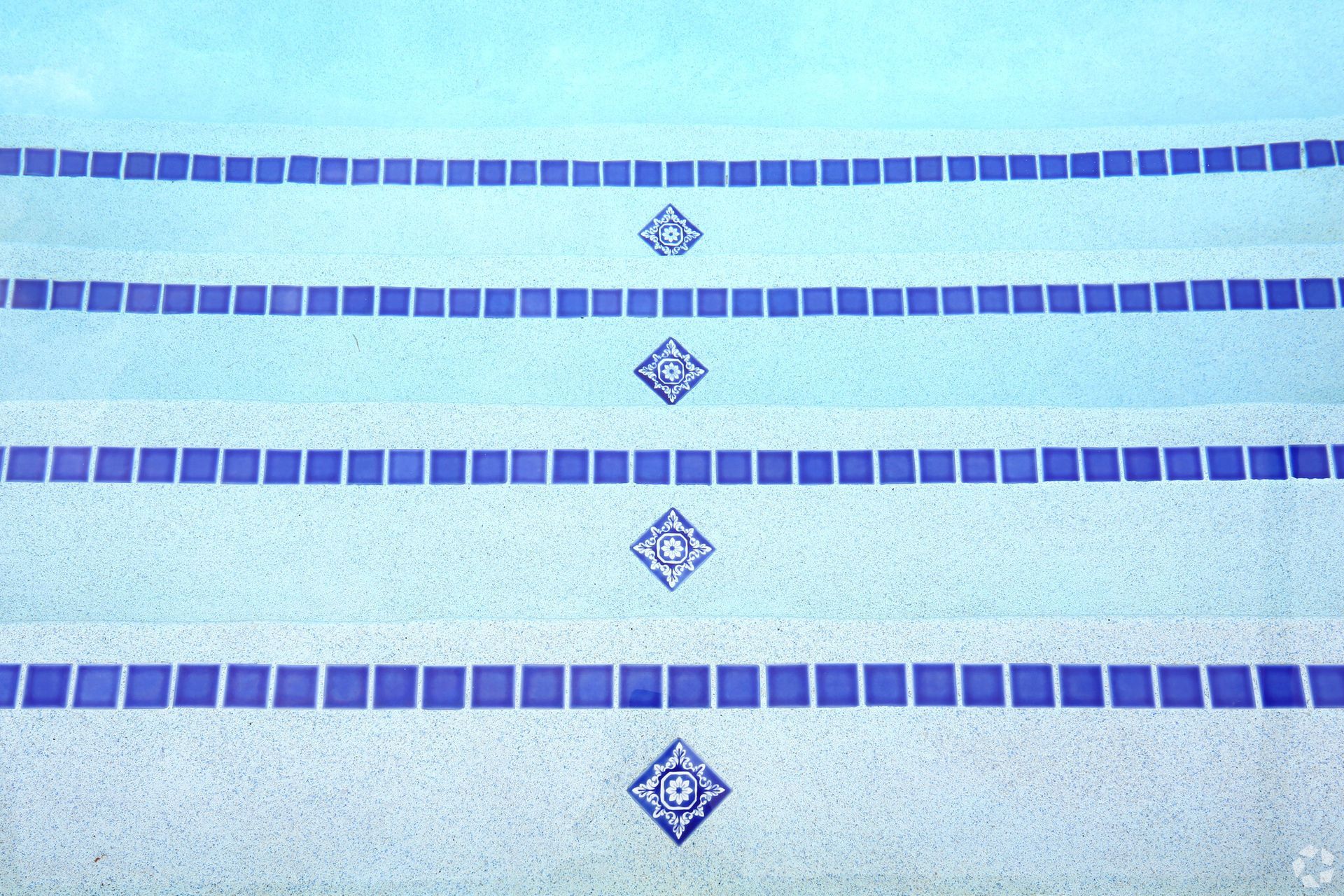 A swimming pool with blue and white tiles on the steps
