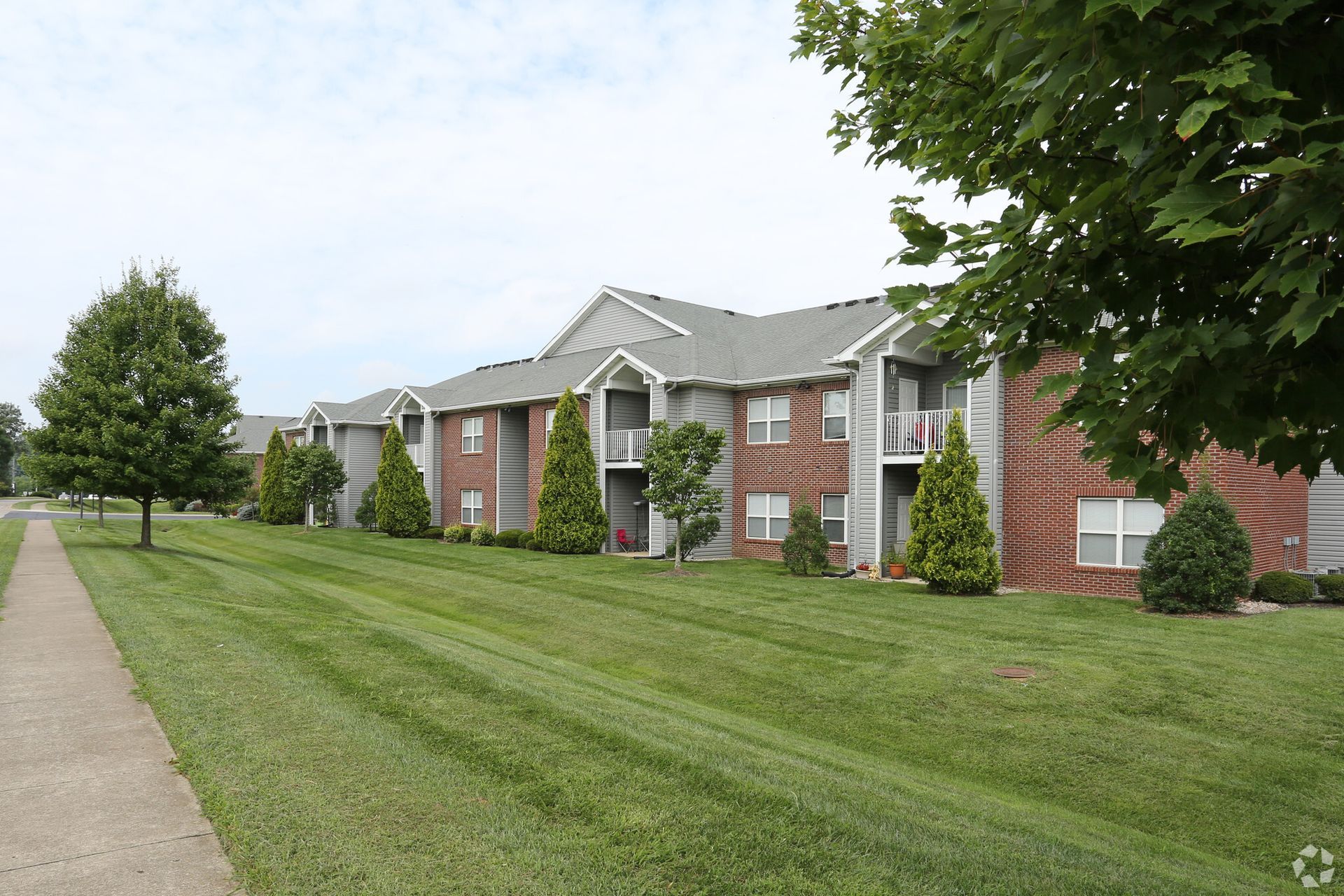A row of apartment buildings with a lush green lawn in front of them.