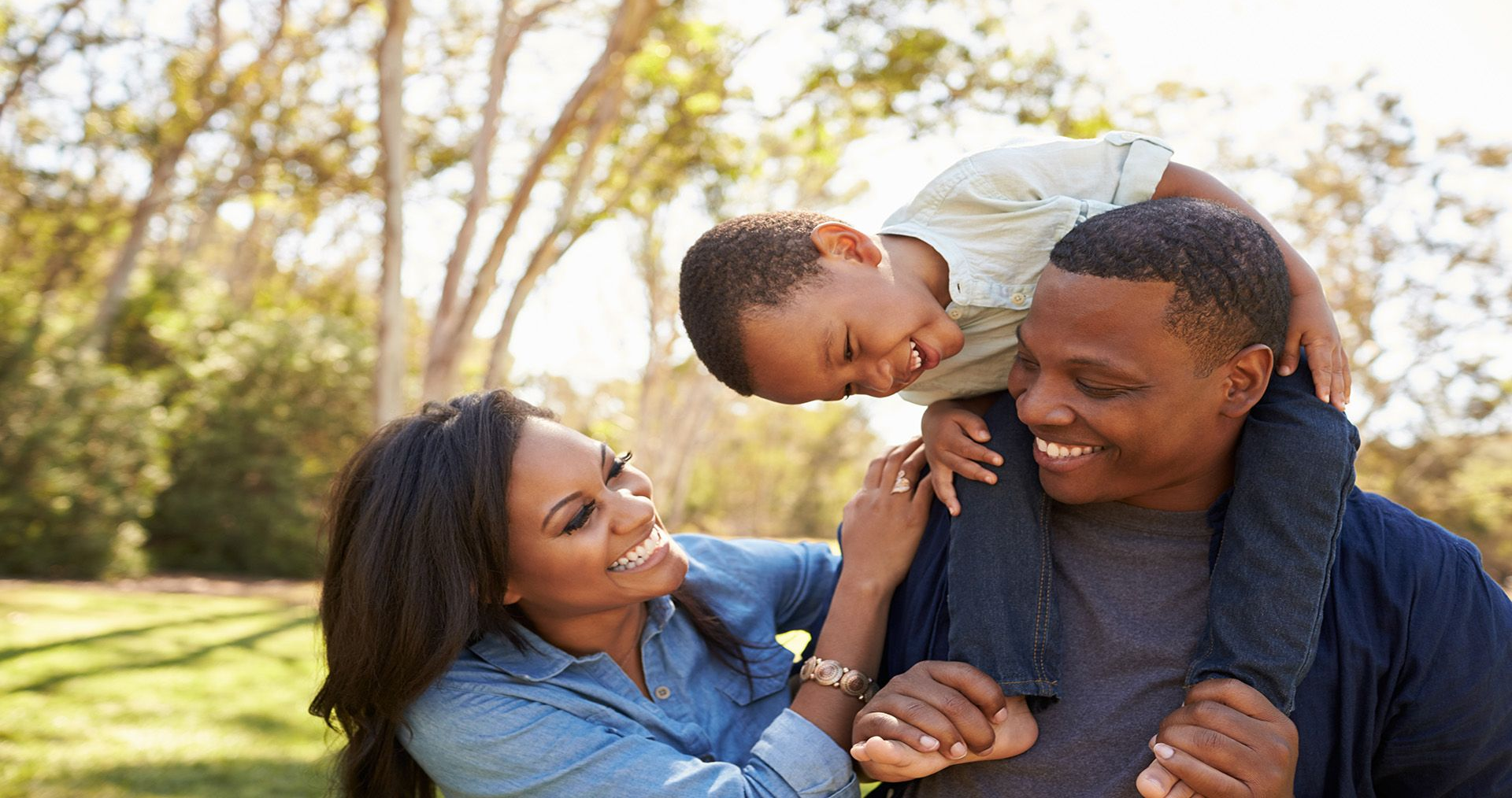 Family smiling together on a sunny grassy lawn outdoors