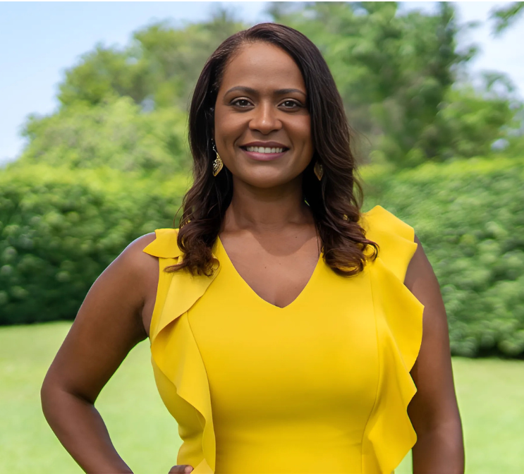 Woman in yellow dress smiles in outdoor setting.