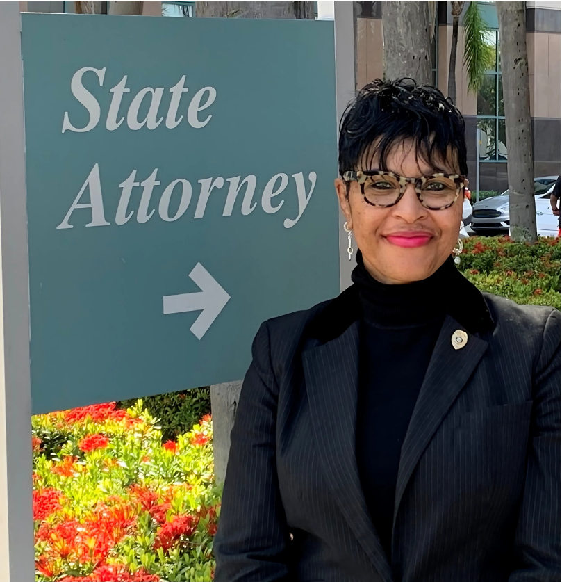 Woman in glasses and suit stands by 