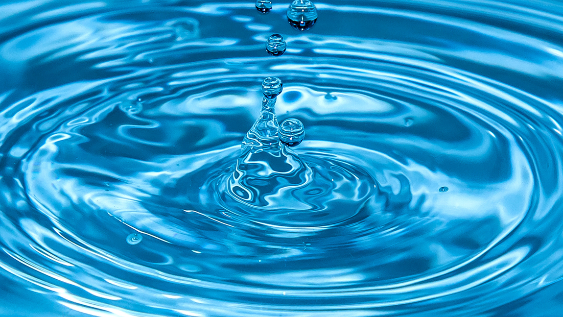Blue water with ripples expanding outward as droplets fall, creating a splash.