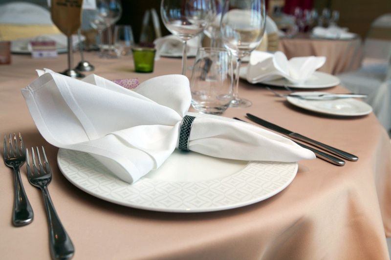 tavolo apparecchiato con tovaglia beige e tovaglioli bianchi