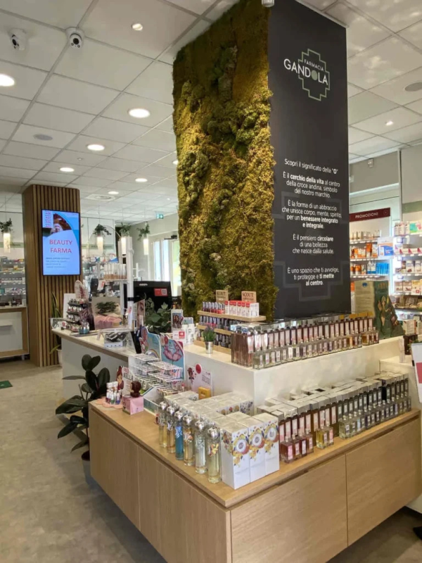 Chiosco espositivo di cosmetici in un corridoio luminoso del negozio, con scaffali pieni di prodotti di bellezza e uno schermo digitale.