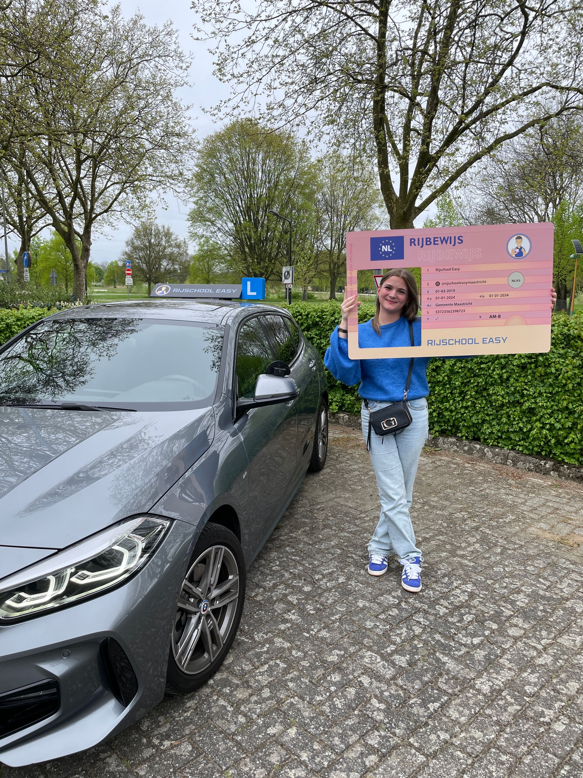Een geslaagde leerling houdt een rijbewijs vast voor de lesauto van rijschool easy.