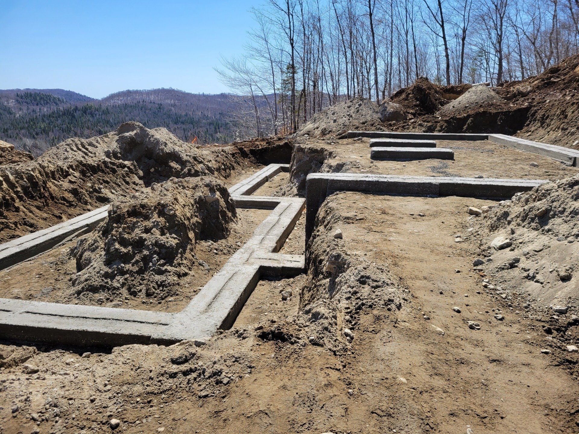 Une fondation en béton est en train d'être construite au sommet d'une colline de terre.