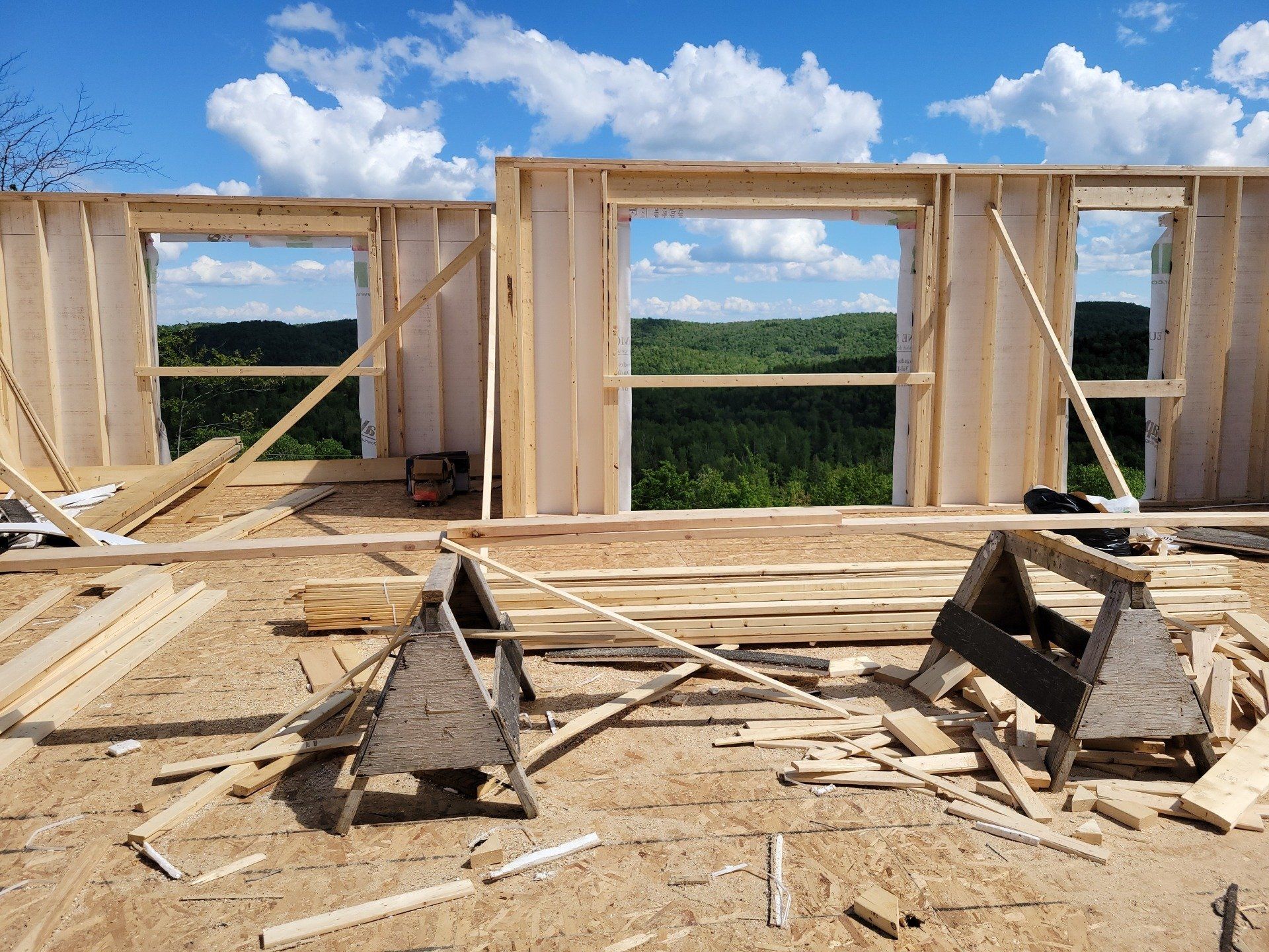 Une maison est en train d'être construite avec beaucoup de bois et beaucoup de fenêtres.