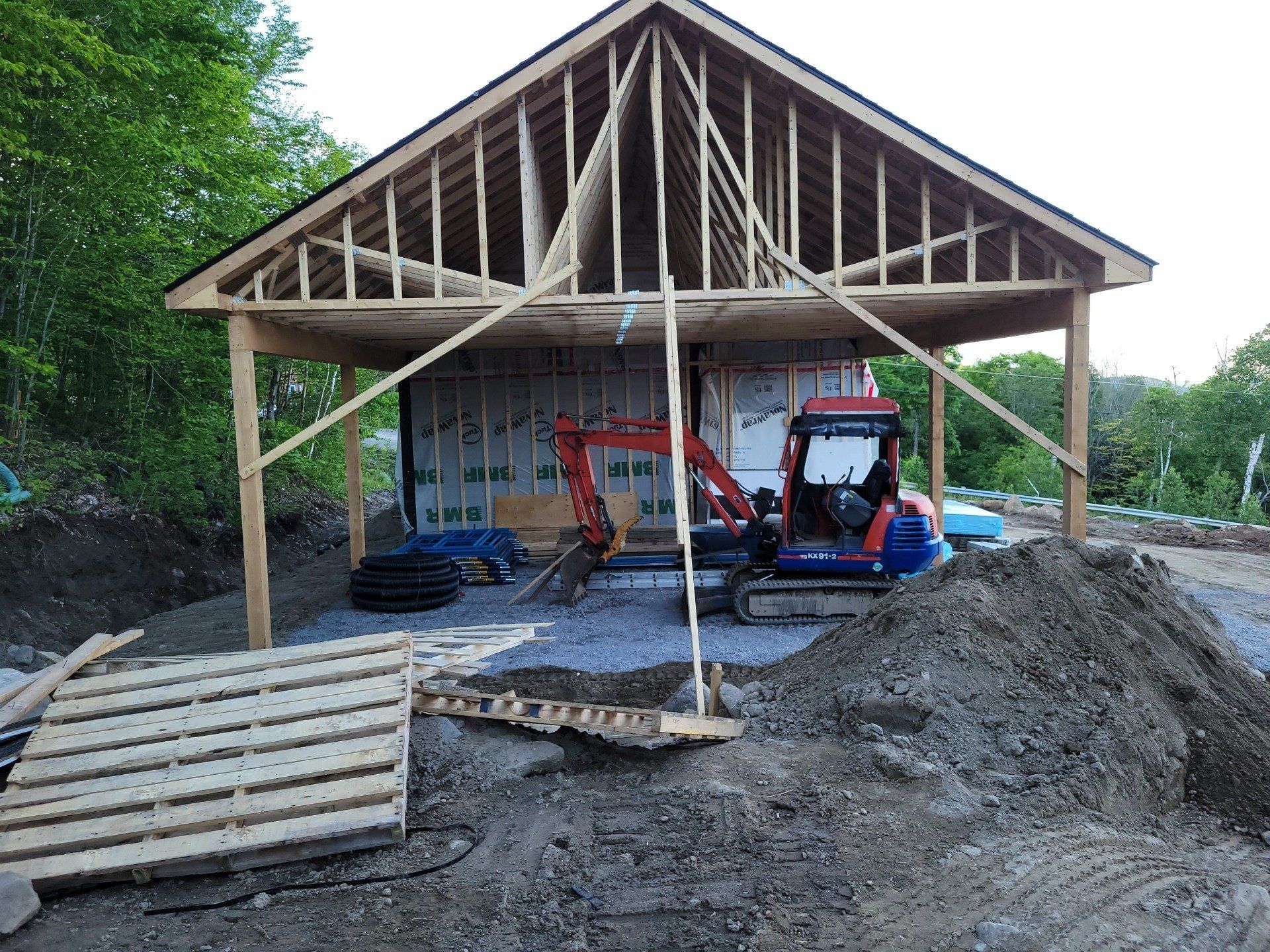 Une petite excavatrice est assise devant un bâtiment en construction