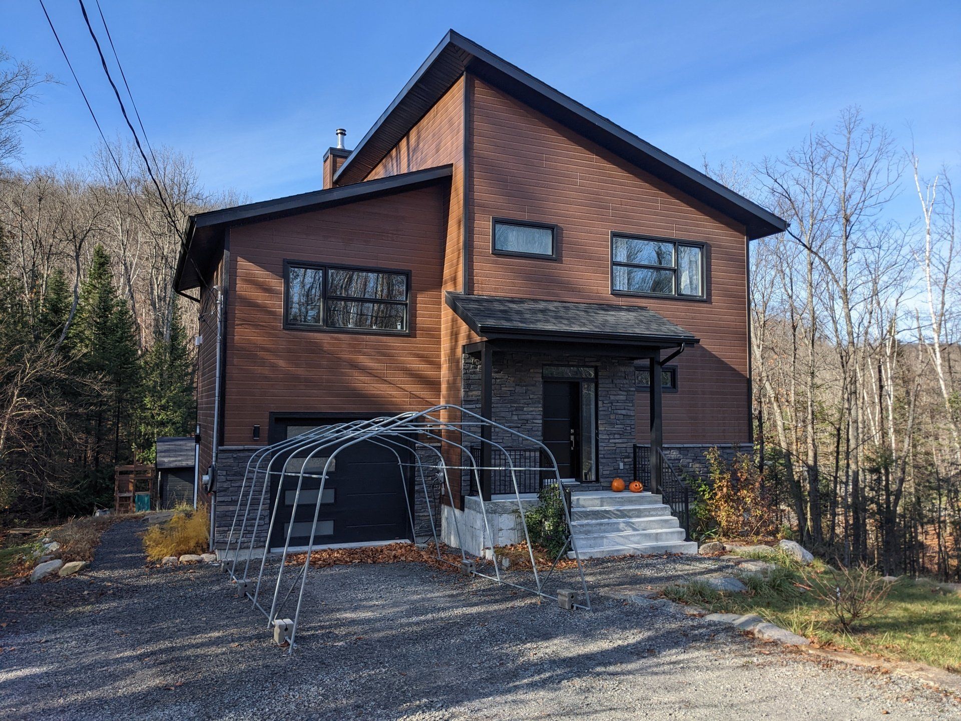 Une grande maison en brique avec un garage et une tente devant.