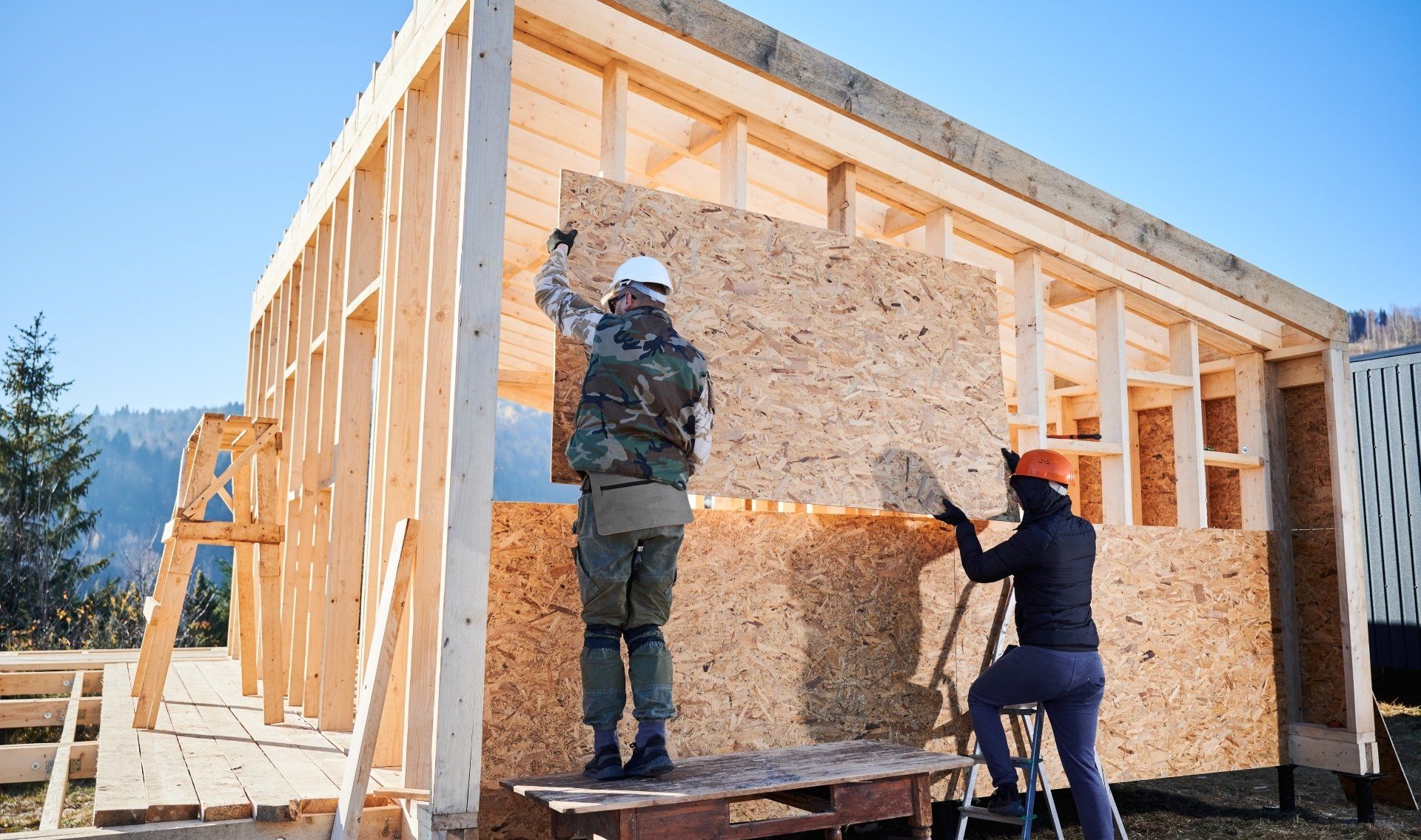 Un homme et une femme travaillent sur une maison en bois.