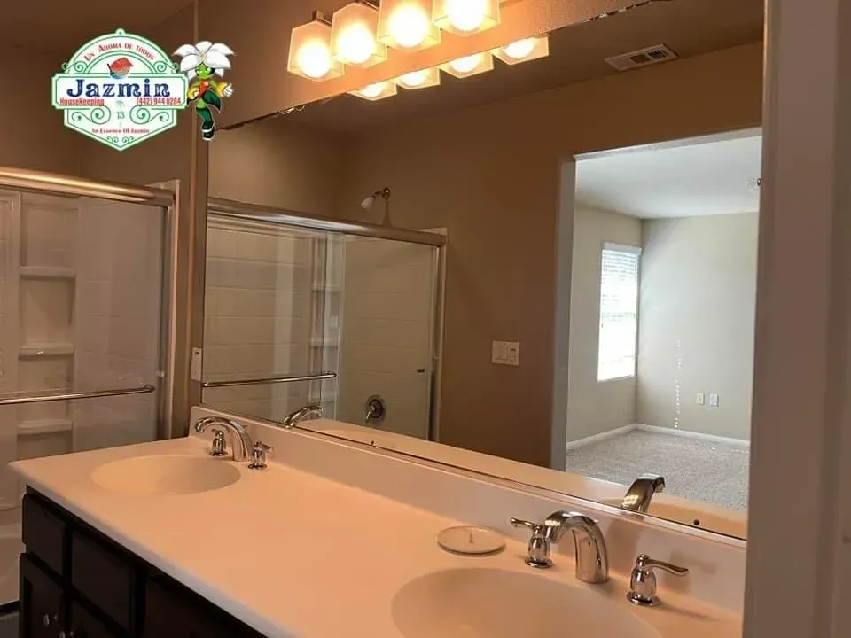Hotel bathroom vanity with large mirror, double sink, and glass shower enclosure