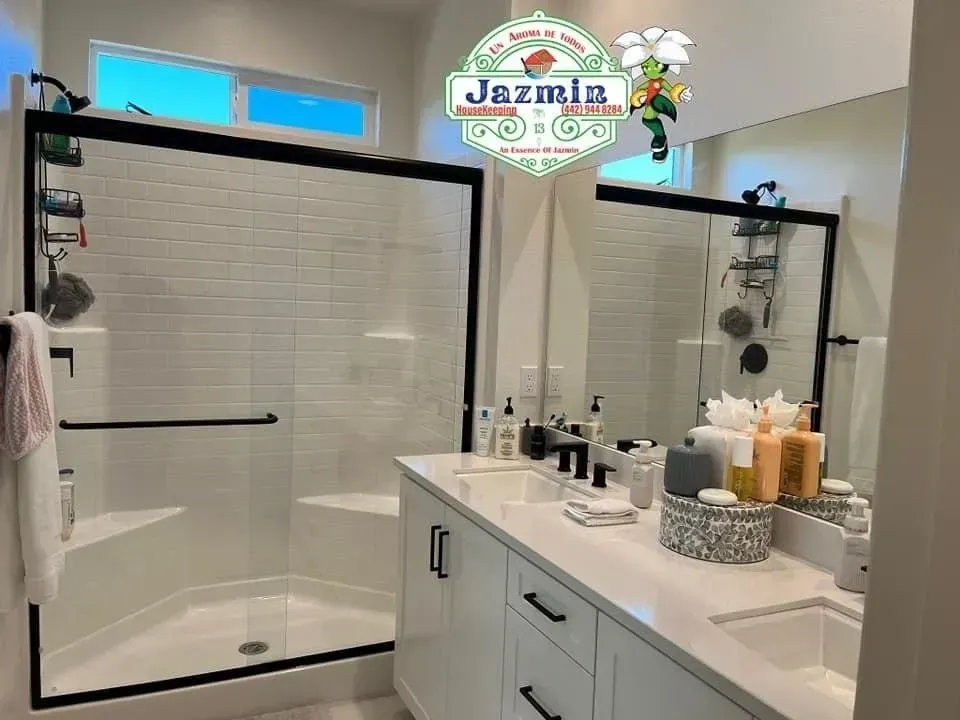 Bright modern bathroom with glass shower, large mirror, and white double vanity counter