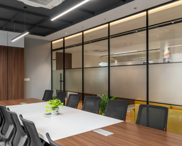 Modern conference room with wood table, black chairs, and glass partition walls