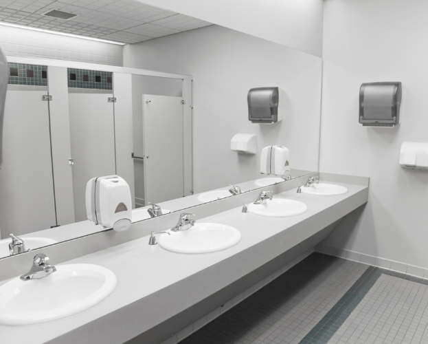 Clean public restroom with long counter sinks, mirrors, and wall-mounted soap dispensers