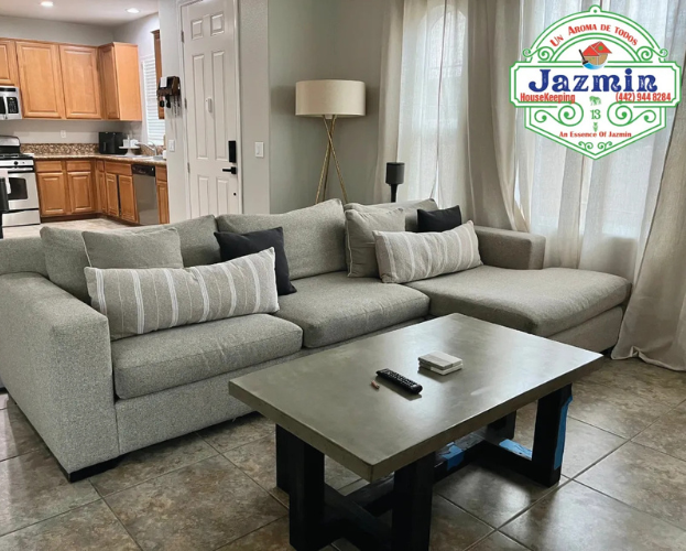 Modern living room with a gray sectional sofa, coffee table, floor lamp, and kitchen in the background