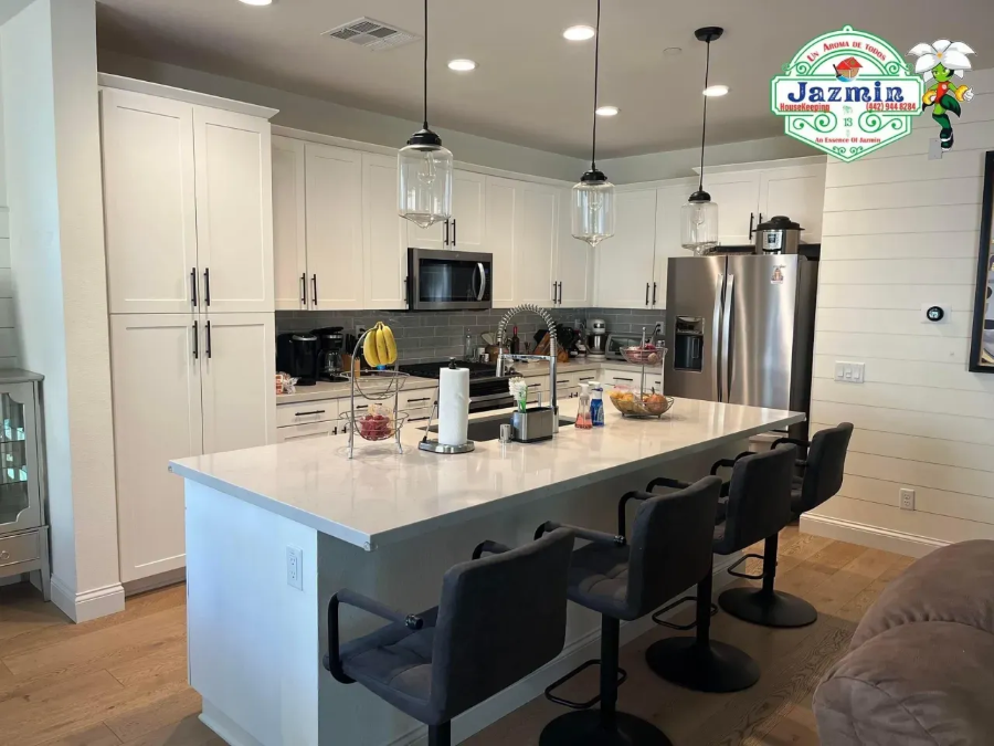 Modern kitchen with white cabinets, island seating, pendant lights, and stainless steel appliances