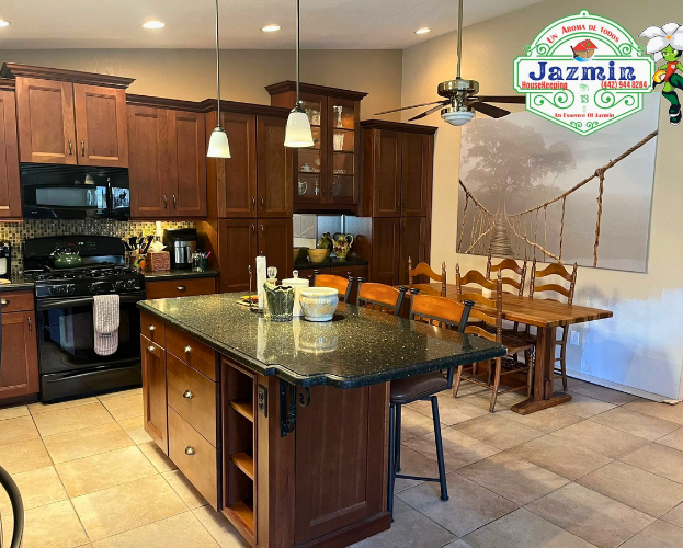Modern kitchen with dark wood cabinets, granite island, tiled floor, and dining table with chairs
