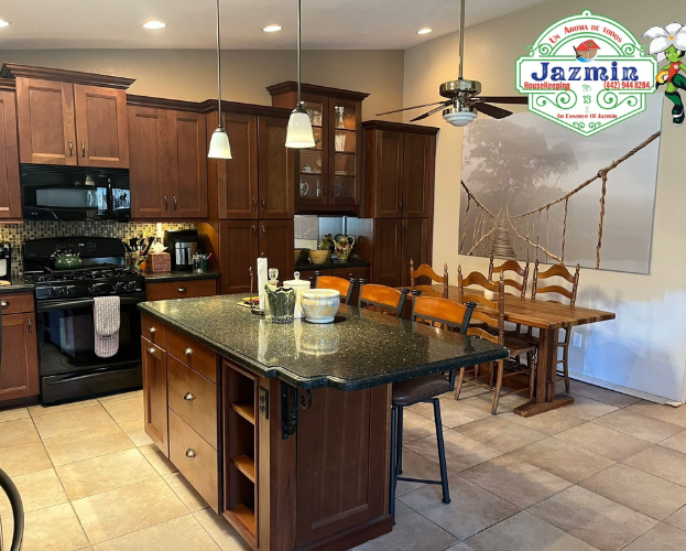 Modern kitchen with dark wood cabinets, granite island, dining table, and pendant lights