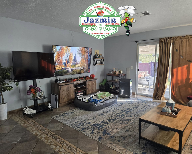 Cozy living room with gray walls, TV, fireplace, patterned rug, and sliding glass door to patio.