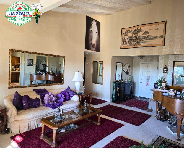 Cozy living room with beige sofa, purple pillows, coffee table, rug, and framed wall art