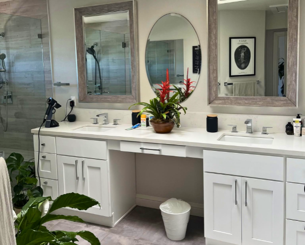 Modern bathroom vanity with double sinks, white cabinets, mirrors, and a red flower arrangement