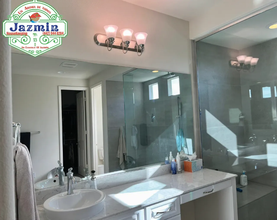 Modern bathroom with double vanity, large mirrors, glass shower, and wall sconces
