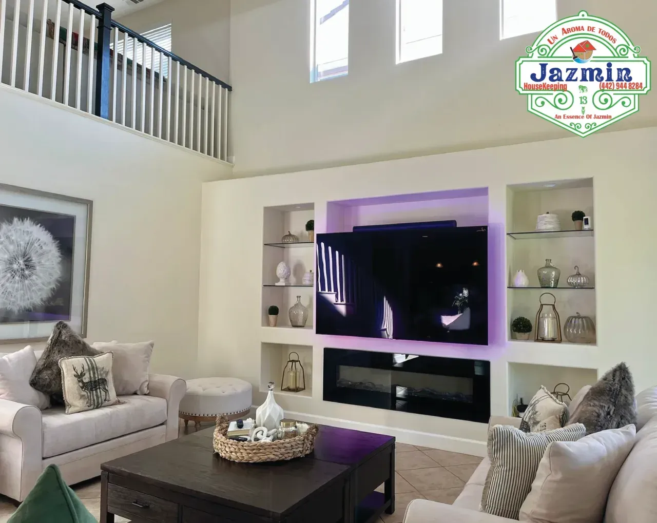 Bright modern living room with white sofas, a dark coffee table, and a TV built into a wall unit.