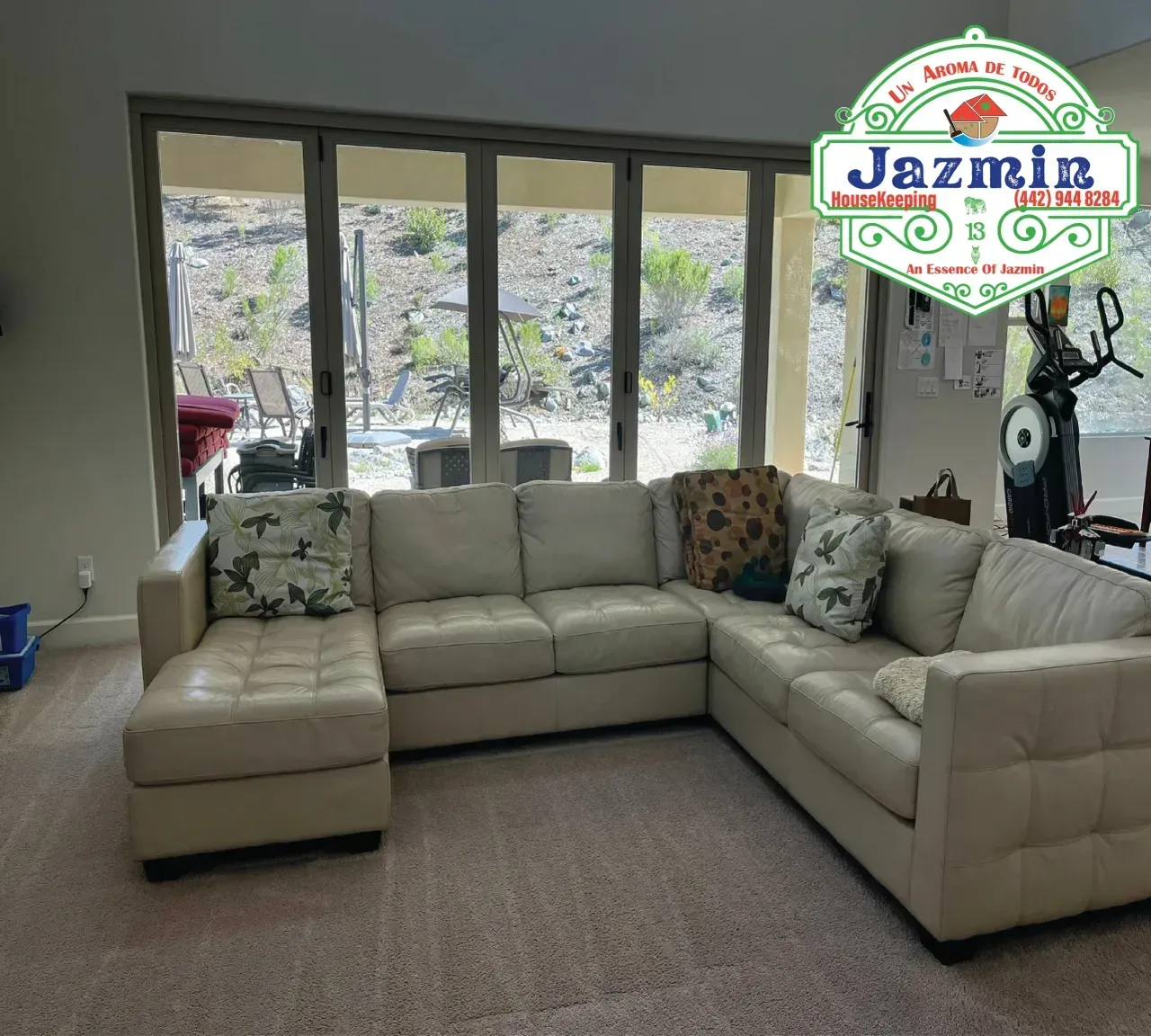 Cream L-shaped sectional sofa in a bright living room with large windows and a rug